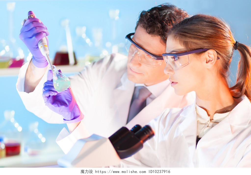 化学实验室场有吸引力的年轻学生和她后博士生导师科学家观察玻璃烧瓶的绿色溶液颜色转变